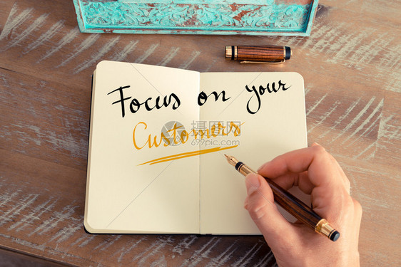 女手写笔记本上用喷泉笔写字的纸条手写文字作为商业概念图象聚焦于您的客户图片
