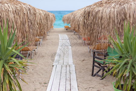 早上通过沙滩椅和茅草伞在美丽的海滩上通往大海的小路浅景深爱琴图片