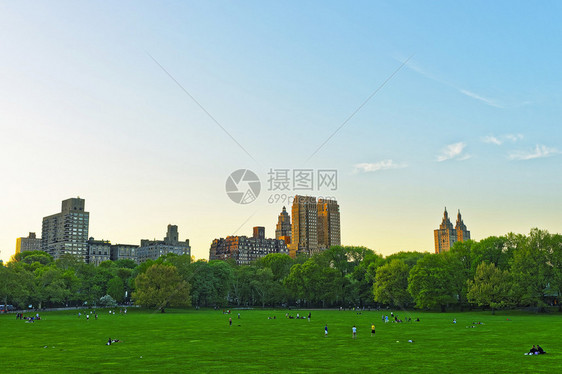 在美国纽约中央公园西部的绿草坪和曼哈顿天线上放松观光者图片