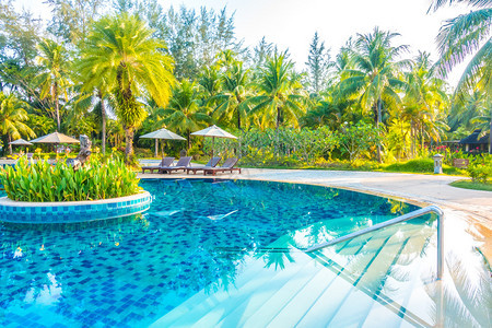 美丽的豪华雨伞和椅子在酒店度假村游泳池周围的游泳池旁图片