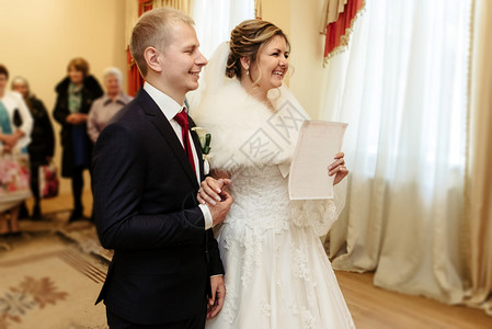 快乐华丽的新娘和时尚的新郎拿着正式文件结婚登记册图片