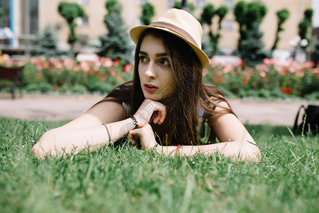 戴着帽子的年轻美女躺在草地上图片