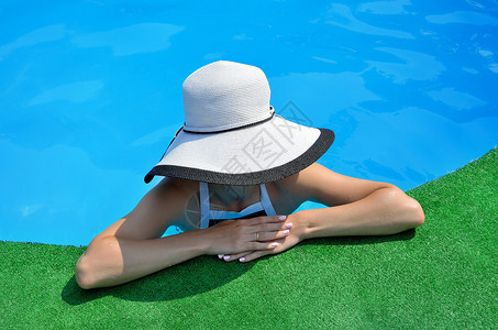 游泳池里戴太阳帽的年轻女子图片