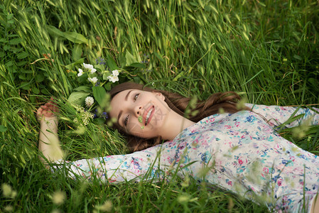 花圈里的美丽的年轻女子躺在公园户外图片