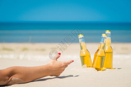 阳光明媚下沙子里的冰镇啤酒瓶图片