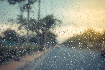 汽车挡风玻璃和雨滴在路面背景下以图片