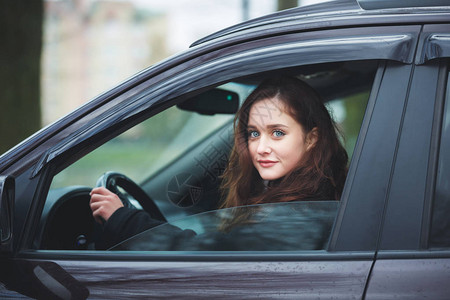 在雨中驾驶汽车的年轻有魅力的女人图片