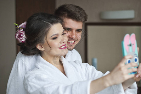 年轻微笑的情侣在酒店房间里自拍图片
