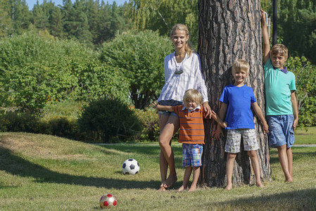 公园里幸福的一家人年轻漂亮的女人和三个男孩站在一起图片