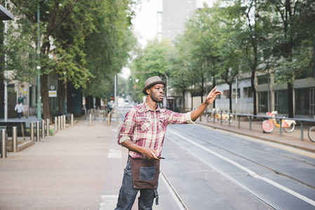 年轻英俊的阿夫罗男子的膝盖型小腿试图叫出租车在城里举起手来图片
