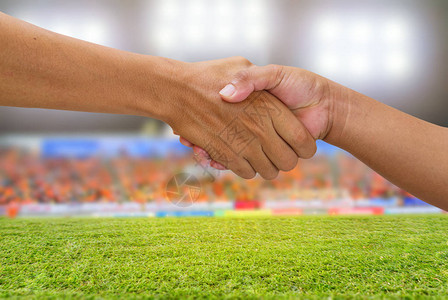 在一个商业对手队球员中握手在足球场背图片
