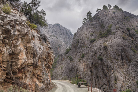 土耳其Goyynuk峡谷远山近山岩石树木山路长板绳围栏和灰色风背景图片