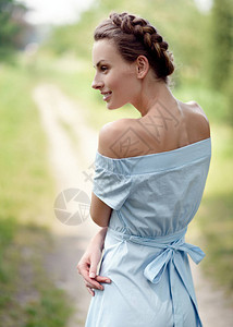 穿着蓝色礼服的年轻漂亮女孩夏天在公园里穿蓝裙子的夏日女郎回来摆姿势图片