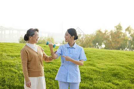 年轻女护工示范给老奶奶康复运动图片