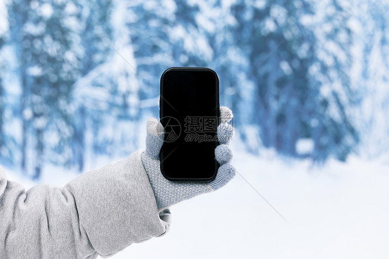 冬日雪地里使用手机特写图片
