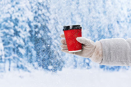 雪地里手拿咖啡杯手部特写图片