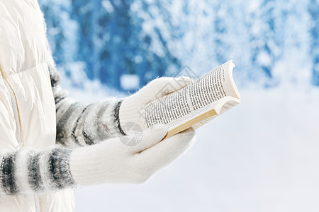 雪地里看书的女子特写图片