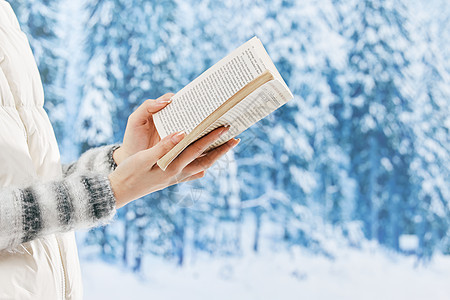 雪地里看书的女子特写图片