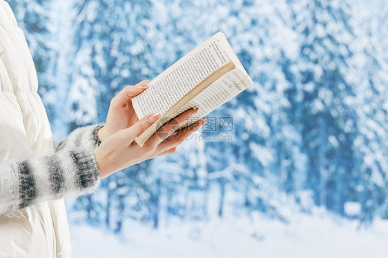 雪地里看书的女子特写图片