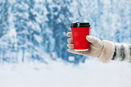雪地里手拿咖啡杯手部特写图片
