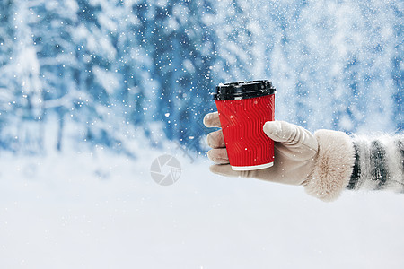 雪地里手拿咖啡杯手部特写图片