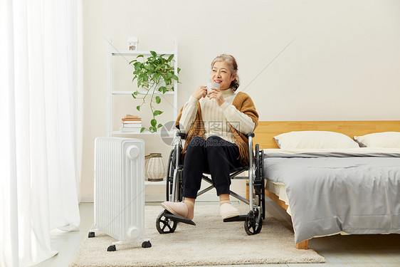 坐轮椅的奶奶居家使用移动暖气片图片