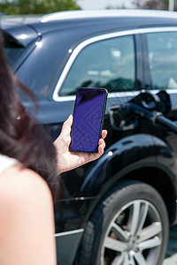 青年女人使用手机自助充电汽车图片