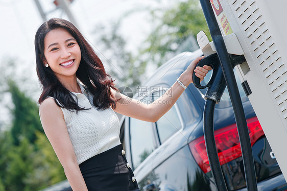 从充电桩取充电的漂亮青年女人图片