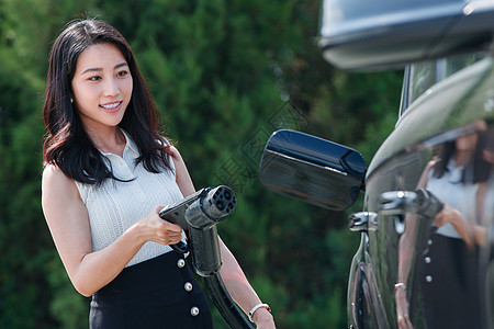 青年女人拿着充电准备给汽车充电图片