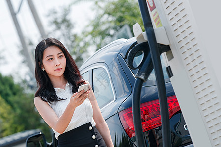 青年女人使用手机自助充电汽车高清图片
