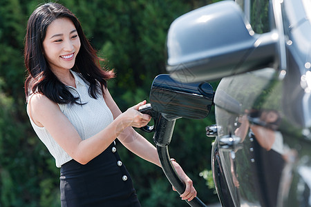 漂亮的青年女人给汽车充电图片