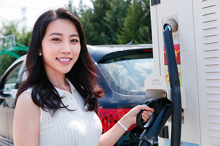 从充电桩取充电的青年女人图片