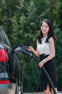 漂亮的青年女人给汽车充电图片