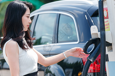 从充电桩取充电的青年女人图片