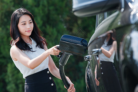 青年女人拿着充电准备给汽车充电图片