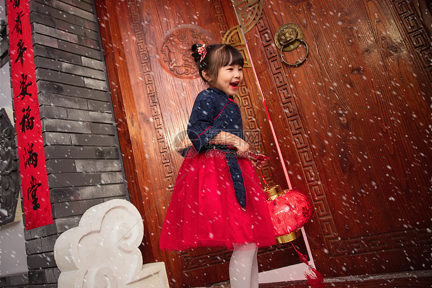 雪中的小女孩手提红灯笼庆祝新年图片