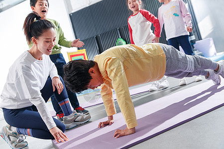 做俯卧撑男孩东方儿童在教练的指导下进行体能训练背景