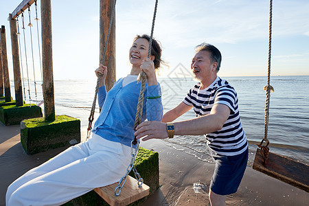 快乐的老年夫妇在海边荡秋千图片