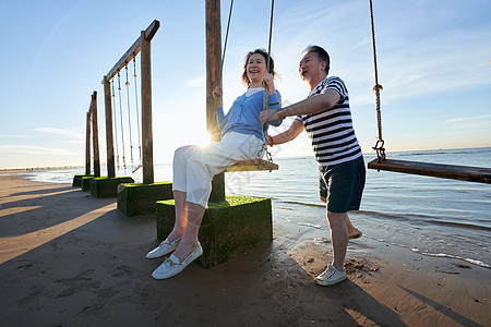 快乐的老年夫妇在海边荡秋千图片