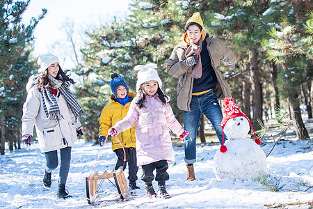 在雪地上玩雪橇的一家人图片