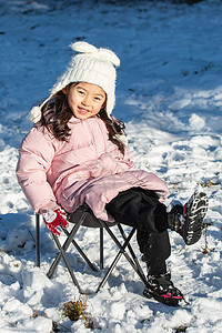 快乐的小女孩坐在雪地上玩耍图片