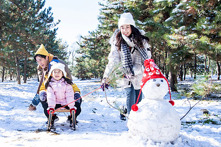 在雪地上玩雪橇的一家人图片