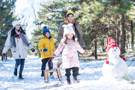 在雪地上玩雪橇的一家人图片