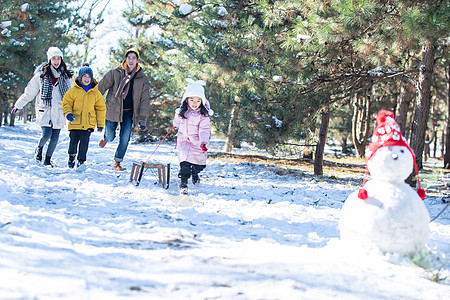 在雪地上玩雪橇的一家人图片