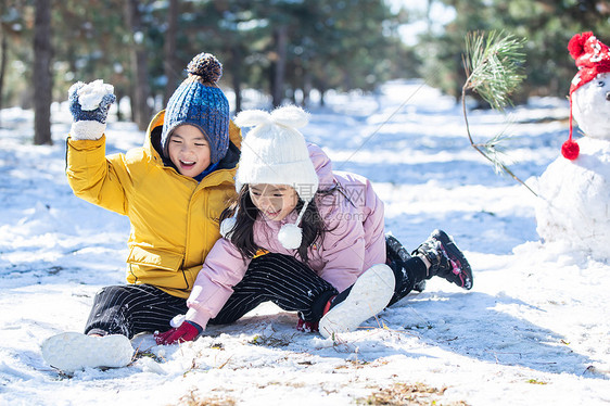 坐在雪地上玩耍的儿童和雪人图片