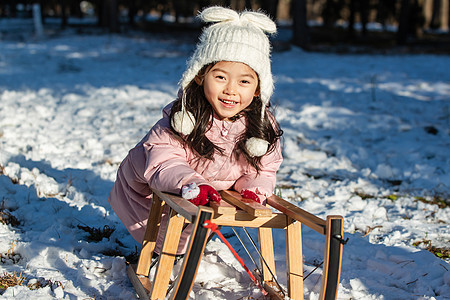 快乐的小女孩在雪地上玩雪橇图片