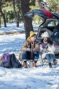 雪地风光坐在汽车旁的青年夫妇背景
