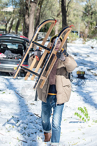 雪地上步行举着雪橇的青年男人图片