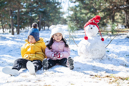 坐在雪地上玩耍的儿童和雪人图片