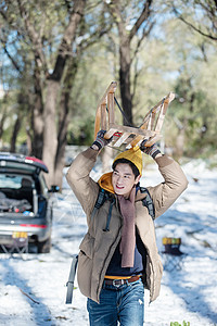 雪地上步行举着雪橇的青年男人图片